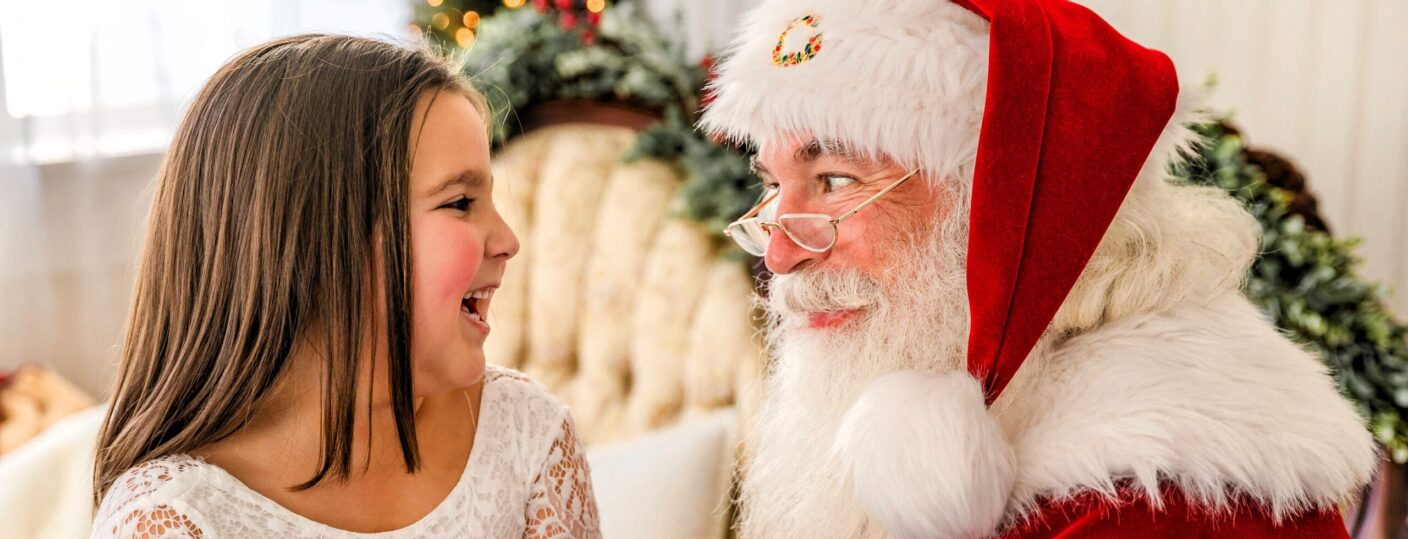 Santa and an older girl looking at each other and sharing a laugh.